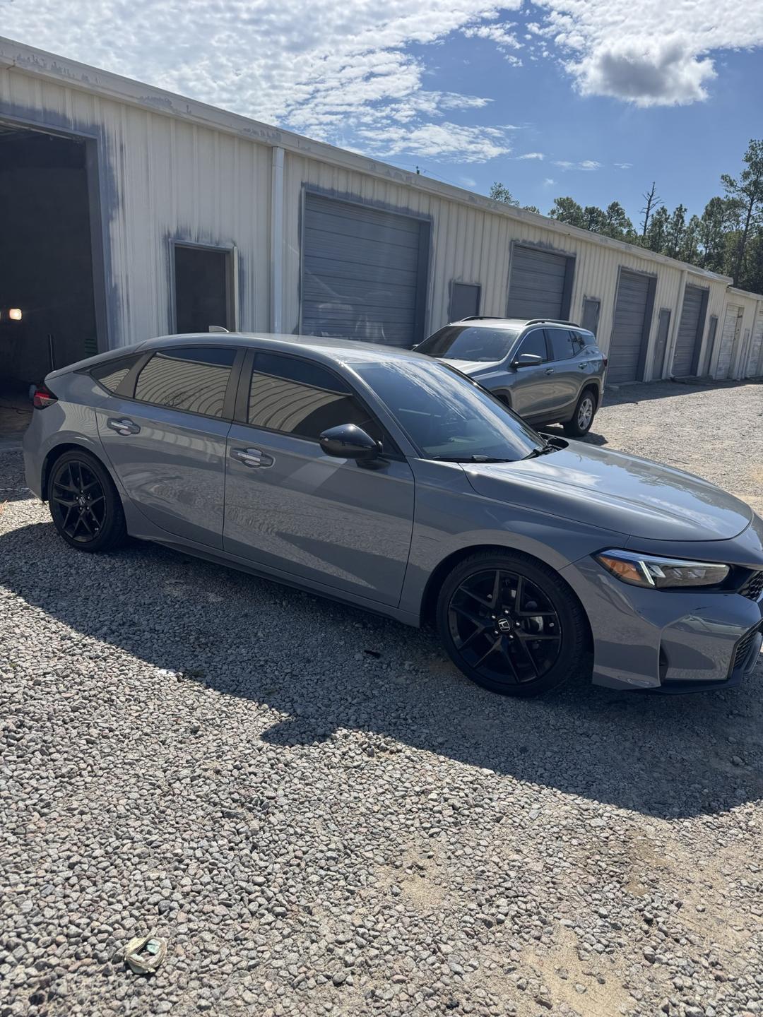 Gray Honda Civic with tinted windows on the gravel lot