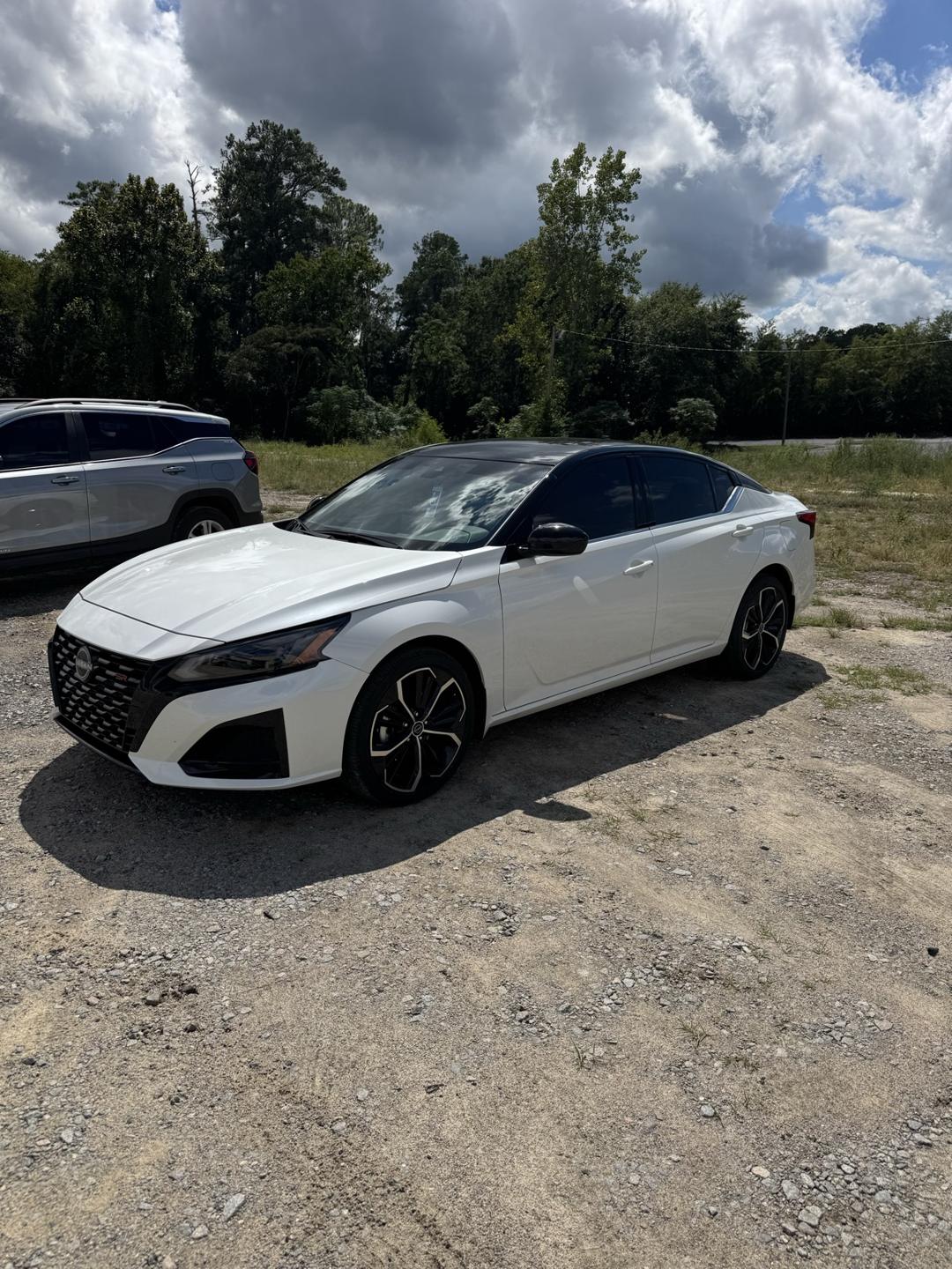 White Nissan sedan with dark tinted windows